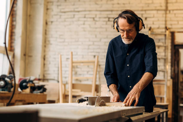 istock Senior carpenter in noise cancelling headphones working on saw machine 1203115496