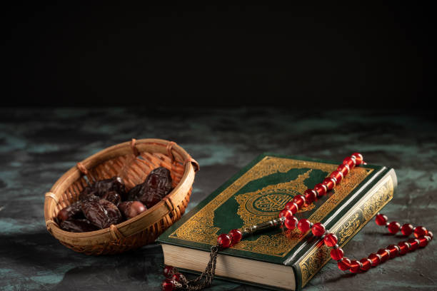 istock Islamic concept: The holy Quran and Tasbih (prayer beads beads) on dark background 1203115502