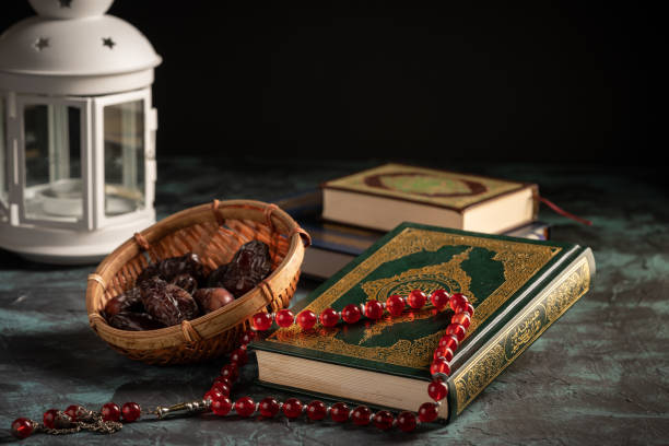 istock Islamic concept: The holy Quran and Tasbih (prayer beads beads) on dark background 1203115538