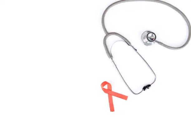 Flat layout of a red ribbon besides a stethoscope, isolated in white background