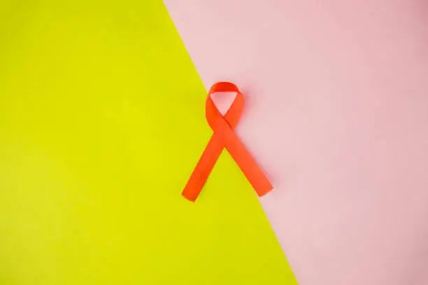 Flat layout of a red ribbon lying, isolated on dual layer paper yellow and pink background