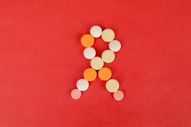 Flat layout of arranged tablets making shape of a ribbon, isolated in red cardboard background