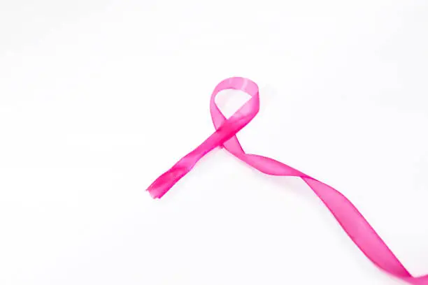 Pink ribbon lying with long knot, isolated in white background