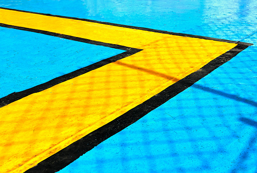Black and yellow geometric lines are painted on a bright blue metal ship floor, serving as guides for passengers during emergency situations.
