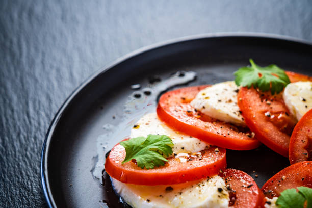 istock Caprese salad on black stone background 1203117599