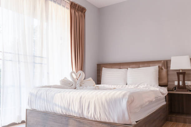 istock Bed room with towel folded in swan shape on bed sheet 1203118500