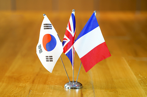 Three flags on the table. Flags of South Korea, United Kingdom and France. Flags of South Korea, France and UK on the table during a meeting of foreign ministers of South Korea, France and UK.