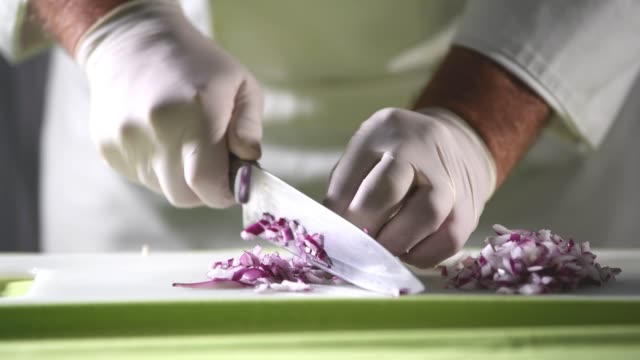 Chef cutting fresh red onion on a cutting board