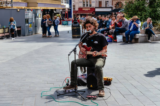 junger künstler spielt e-gitarre am leicester square in london - street musician stock-fotos und bilder