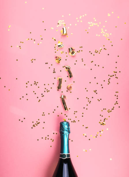 istock Green champagne bottle and streamers flow on pink 1203125957