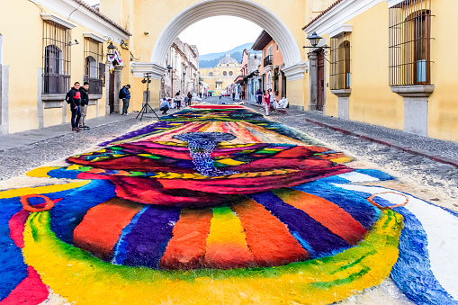 Antigua, Guatemala -  April 14, 2019: Making dyed sawdust Palm Sunday procession carpet during early morning under Arco de Santa Catalina in UNESCO World Heritage Site with famed Holy Week celebrations.