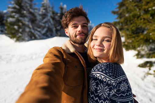 Young couple in love enjoying on the mountain and taking a selfie.