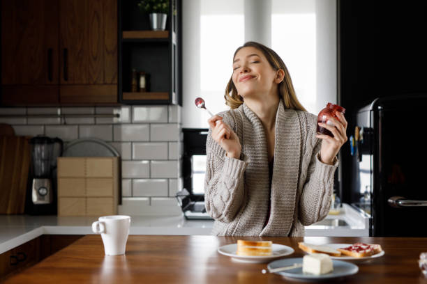 キッチンでジャムを食べる幸せな若い女性の肖像画 - tasting women eating expressing positivity ストックフォトと画像