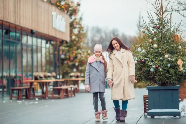 Family of mom and little girl walk together on winter day