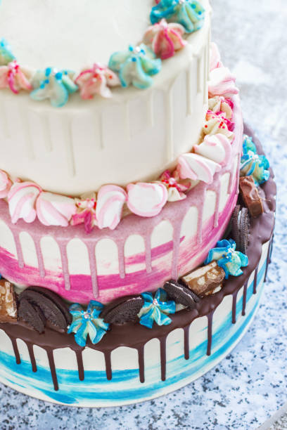 istock Three-tiered colored cake with colored smudges of chocolate on a light background. Picture for a menu or a confectionery catalog, the wedding cake 1203134377