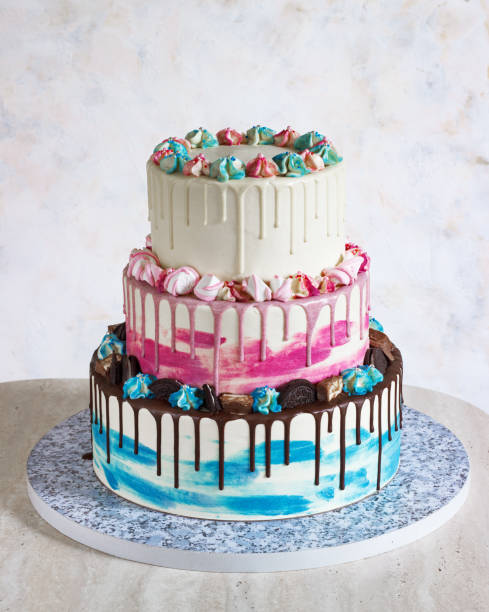 istock Three-tiered colored cake with colored smudges of chocolate on a light background. Picture for a menu or a confectionery catalog, the wedding cake 1203134400