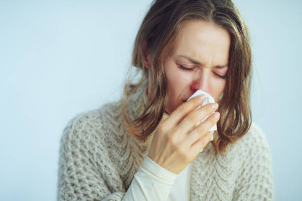 istock woman with napkin coughing on winter light blue background 1203134913