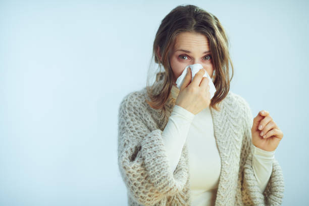 istock female with napkin blowing nose on winter light blue background 1203135003