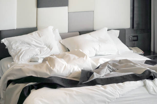 istock Hotel bed after use. Dirty bed pillow blanket room. 1203135781