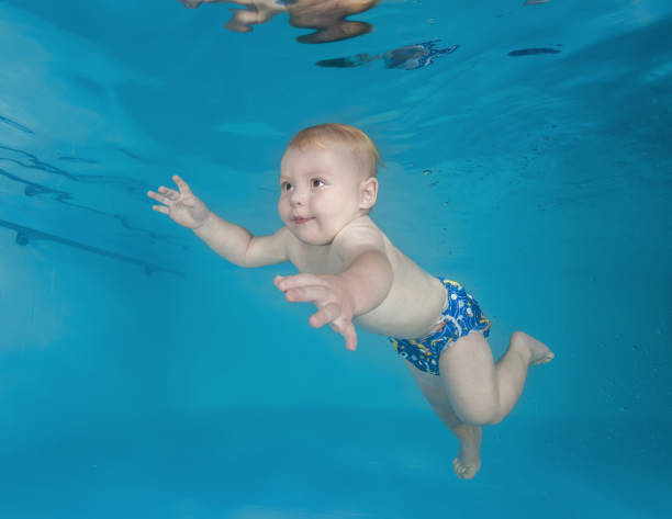 istock Little boy swims underwater in a swimming pool 1203137624