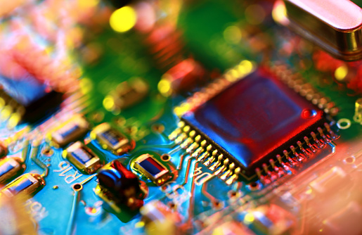 Abstract electronic circuit board in multi-colored lighting, close-up.