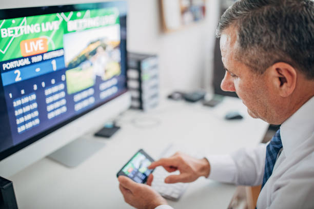 istock Business man using computer and smart phone for live betting 1203144417