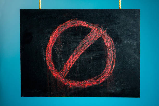 istock Chalk board is suspended with a pattern of a red prohibition sign on a blue background. copy space 1203145920