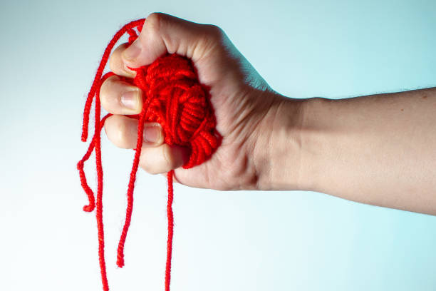 istock male hand squeezes a red heart from threads and red threads hang down concept on a light background copy space close up 1203145985