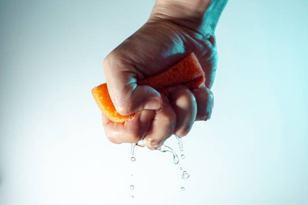 istock male hand squeezes a sponge for washing with water and drops fall down concept on a light background copy space close up 1203146025