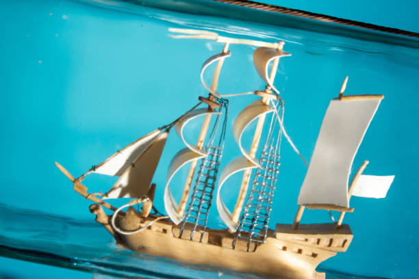 istock ship in a glass bottle at an angle on a blue background. close up, copy space 1203146052