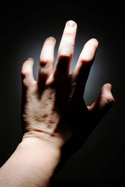 istock male hand on a dark background isolate. copy space close up 1203148323