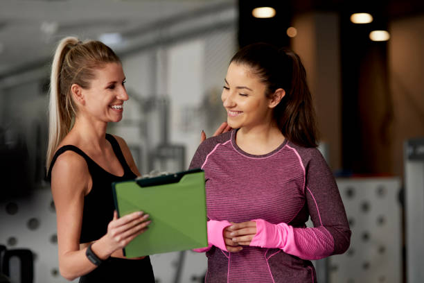 istock Cheerful instructor and woman at gym 1203148576