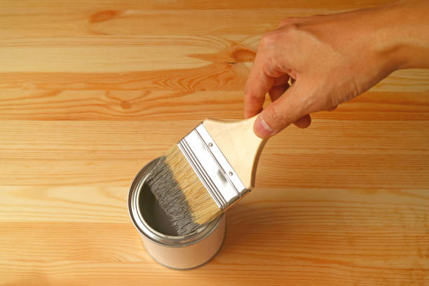 istock Hand holding paintbrush with paint on the wood plank 1203149482