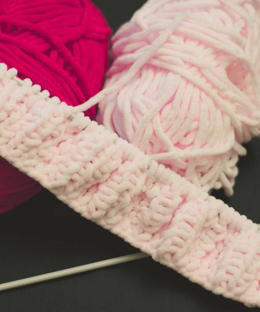 istock Crimson and pink threads for knitting on a black background. Knitting needles 1203152966