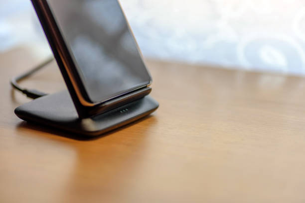 istock smartphone wireless charging on charging stand on wooden table 1203153167
