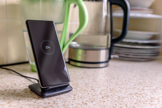 istock smartphone wireless charging on charging stand with 27 percent icon on screen on kitchen tabletop 1203153272