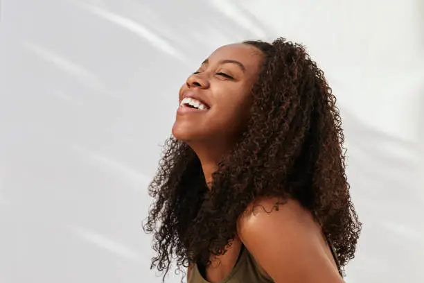 Photo of Young woman laughing with her eyes closed on a gray background