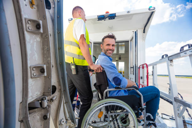 service man helping disabled passenger to enter on board at airport - entering airplane imagens e fotografias de stock