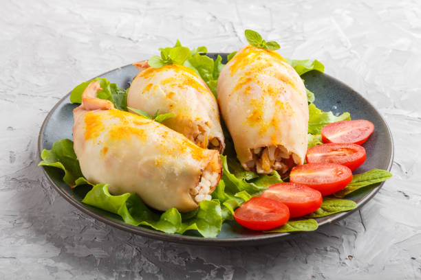 istock stuffed baked squid with greens on a blue ceramic plate on a gray concrete background, side view, close up. 1203158437