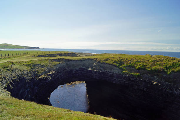 The Bridge of Ross. A natural bridge formed by the Ross Sandstone of Carboniferous age. County Clare, Ireland.The bridges of Ross were a trio of spectacular natural sea bows - at least until two of them fell into the sea. Today there is only one \
