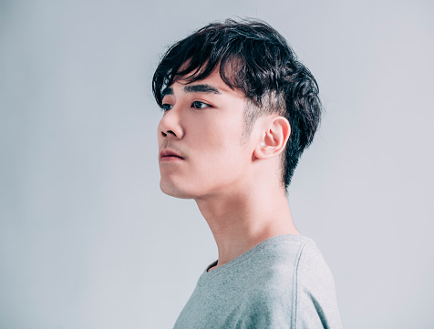 side view of young  asian handsome man isolated on gray background