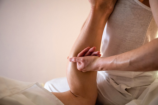 Massage therapist massaging man calves in spa center