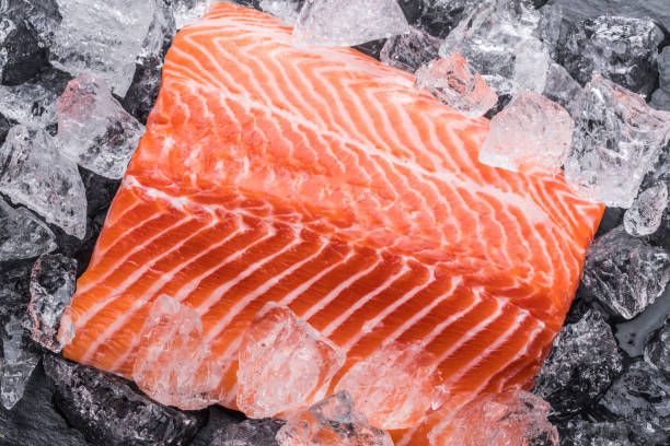 istock Fresh salmon fillet over ice on black cutting board. Top view. 1203162272