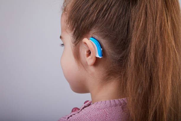 Hearing Aid in Young Girl's Ear Hearing Aid in Young Girl's Ear. Toddler girl wearing a hearing aid. Studio shot ear canal stock pictures, royalty-free photos & images