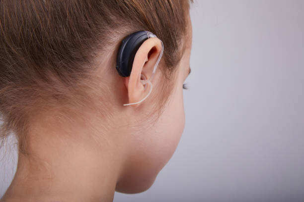 Hearing Aid in Young Girl's Ear. Toddler girl wearing a hearing aid. Studio shot