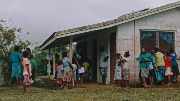 local people villagers waiting outside of a remote isolated village hospital dispensary building for treatment Melsisi, Pentecost Island / Vanuatu - May 10 2019: local people villagers waiting outside of a remote isolated village hospital dispensary building for treatment segregation stock pictures, royalty-free photos & images