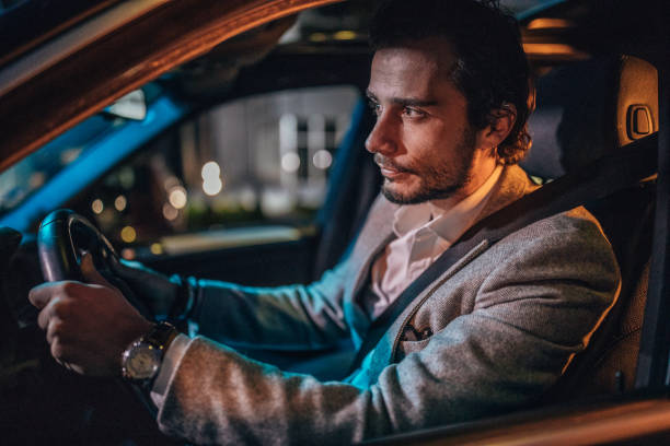istock Man driving a car in city at night 1203168032