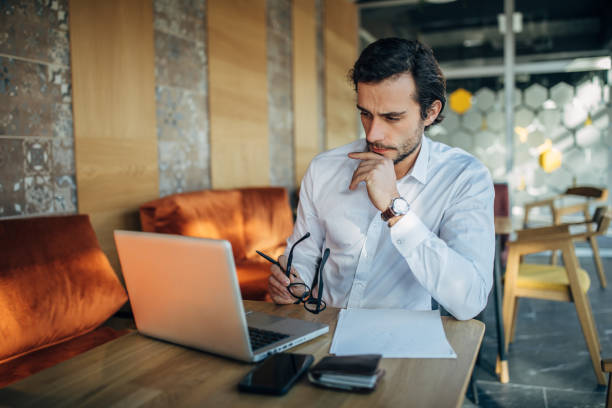 istock Handsome businessman using laptop in cafe 1203168958
