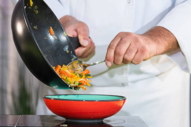 istock Chef moves fried vegetables into a bowl 1203169711