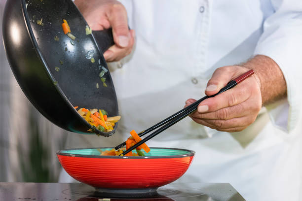 istock Chef uses chopsticks to move fried vegetables into a bowl 1203169713